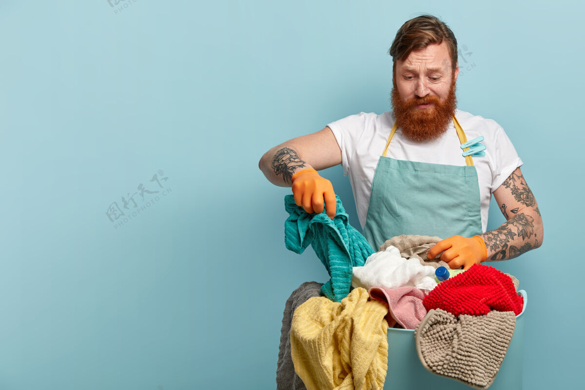 管家管家和家务概念沮丧的红胡子男人拿着毛巾 从篮子里选择脏衣服家务发型选择