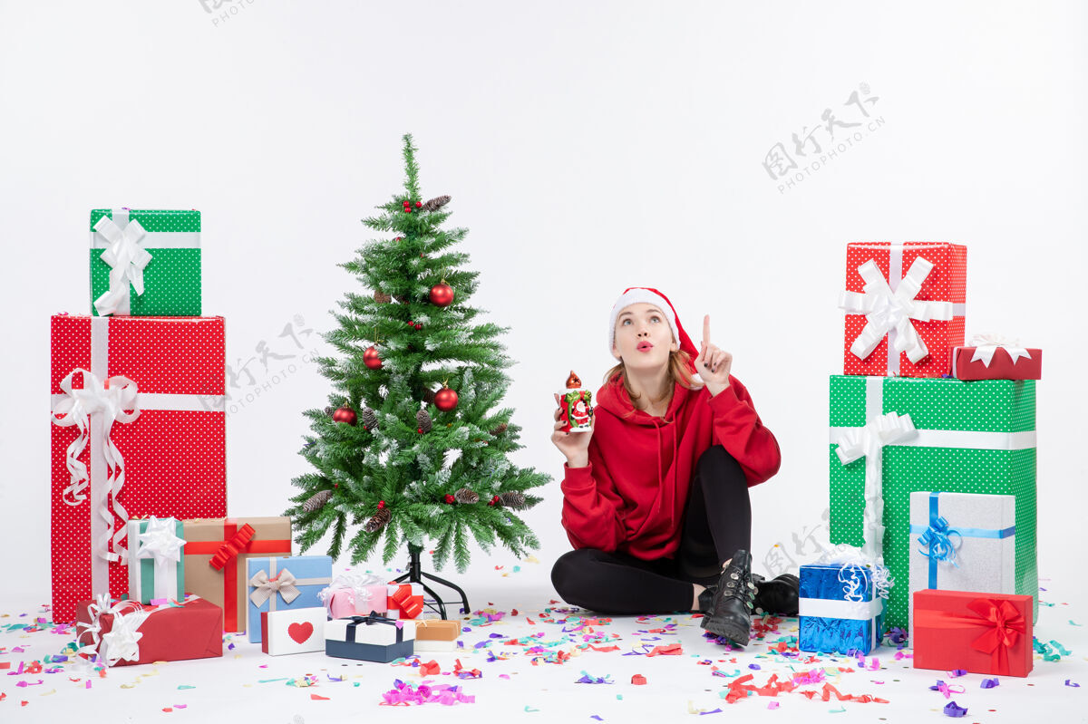 人前视图：年轻女子围坐在白色墙壁上拿着礼物圣诞节日季节性的