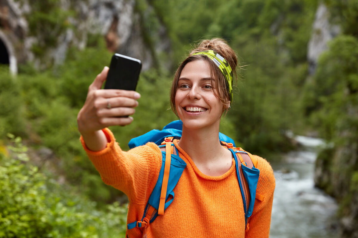 持有女游客用智能手机拍照 在山里有难忘的旅程 站在小溪边风景休息空闲时间