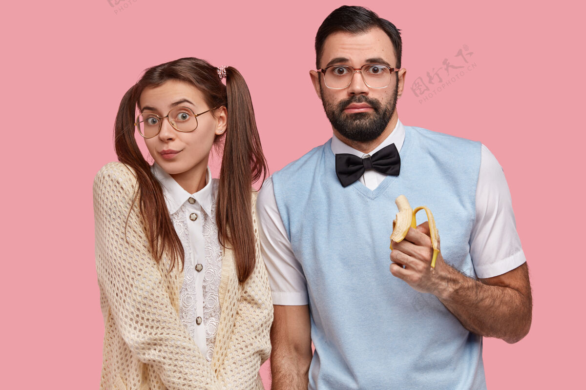 蝴蝶结书呆子夫妇穿着旧时髦的服装 戴着大眼镜 吃着香蕉 神情迷茫优雅同事眼镜