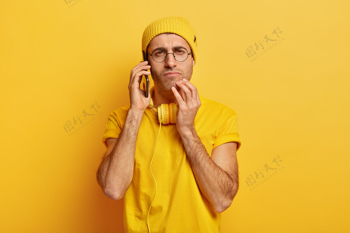 饮料认真细心的年轻人的照片有电话交谈 把现代手机放在耳边 有耳机情感咖啡专注