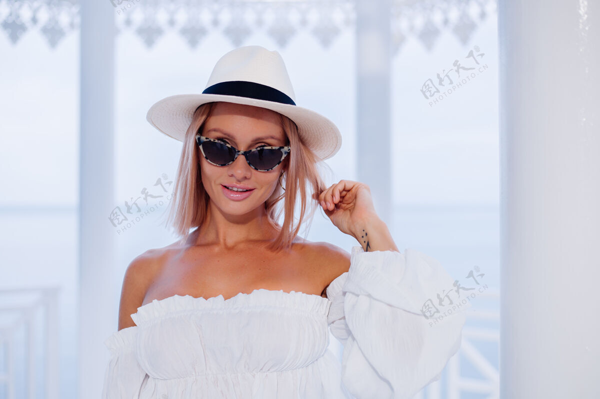 衬衫近距离户外时尚写真的时尚女性在宽大的白色时尚上衣和经典的豪华帽子和豹纹太阳镜女性女人身材