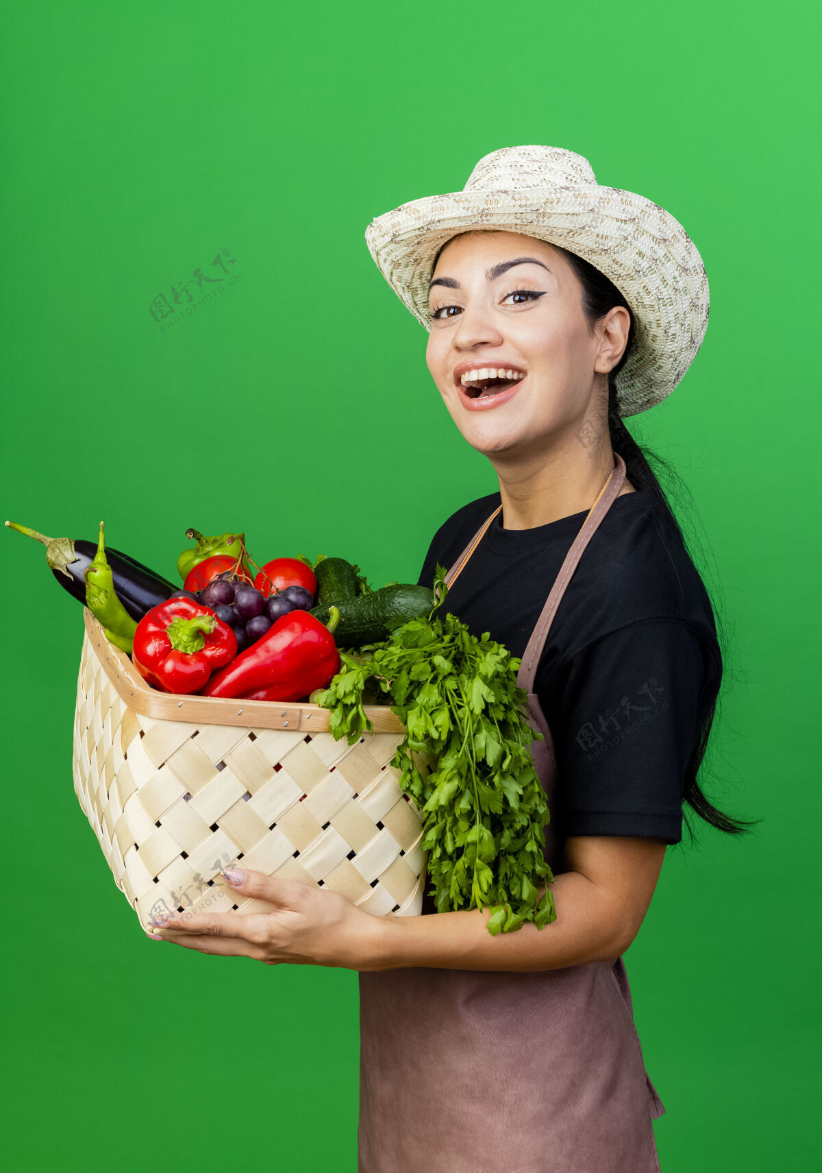 漂亮年轻漂亮的女园丁 围着围裙 戴着帽子 手里拿着装满蔬菜的篮子 满脸笑容站着蔬菜围裙