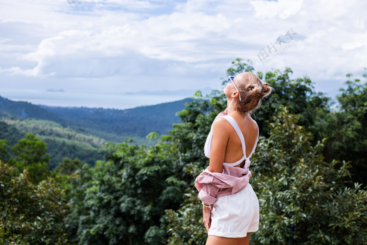 户外欧洲时尚女博主游客站在山顶上欣赏泰国苏梅岛迷人的热带风光时尚户外女性写真年轻户外旅游