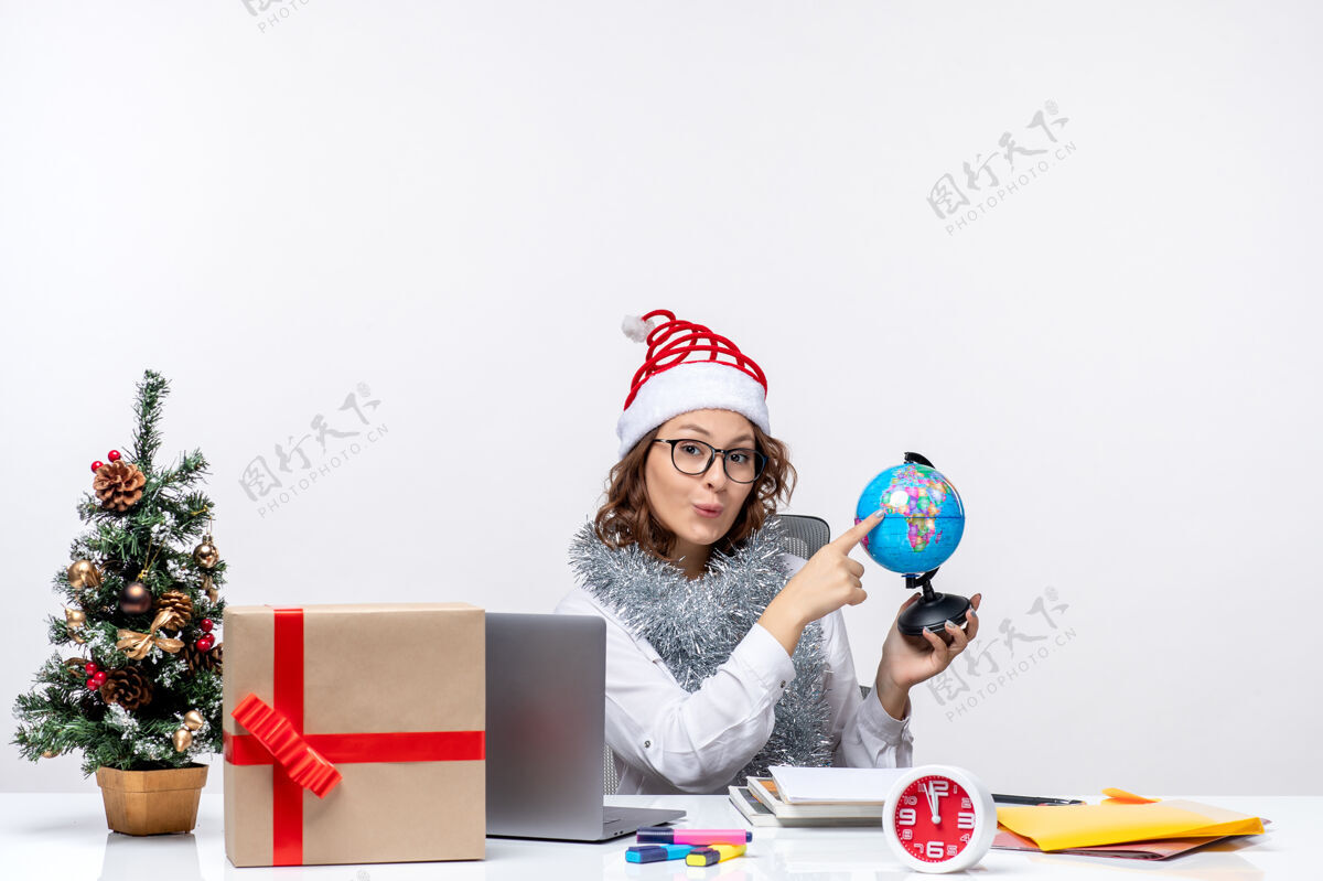 办公室前视图年轻的女工人坐在她的地方举行地球仪在白色的背景白色微笑商务