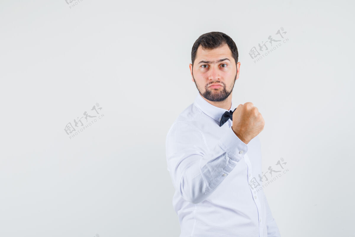 自信年轻男子身穿白衬衫 握紧拳头 看起来很强壮 正面视图拳头表情强壮