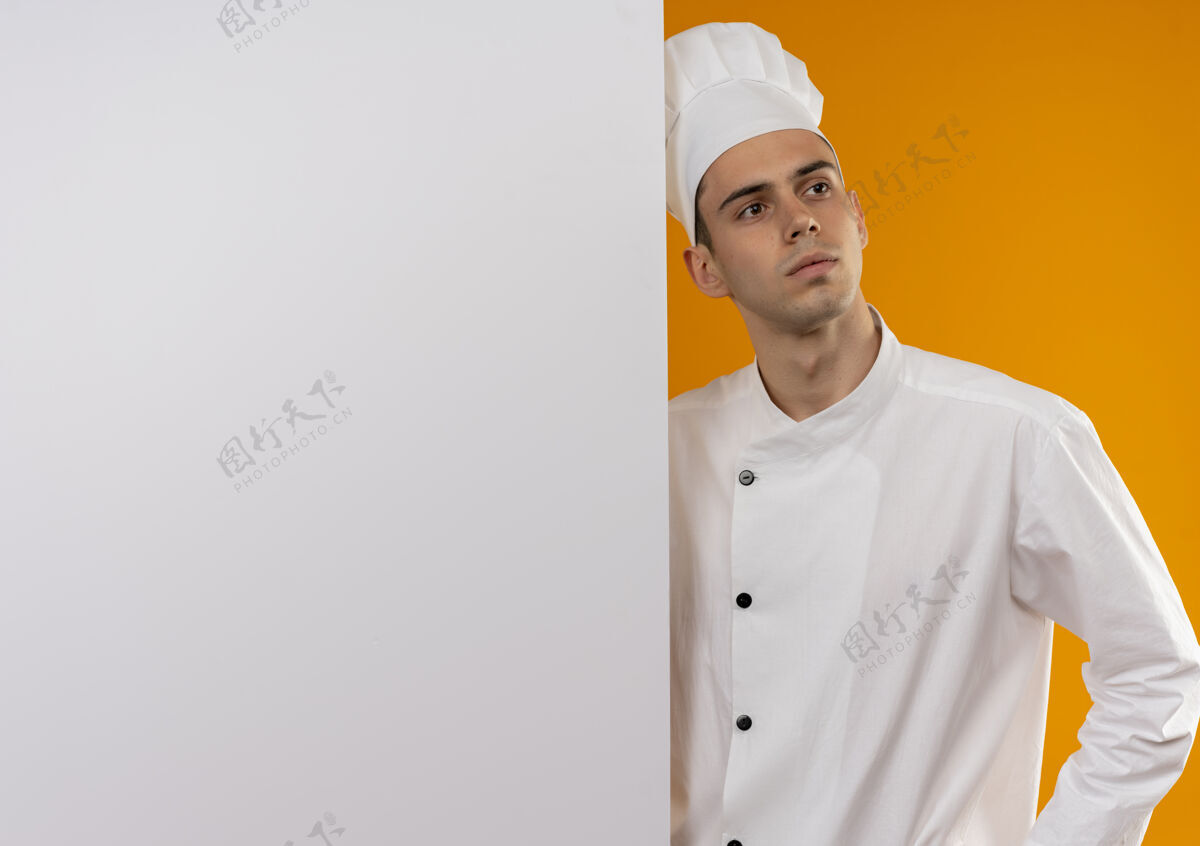 男看着旁边年轻的男酷穿着厨师制服拿着白色的墙 隔离着黄色的墙和临摹的空间酷抱制服