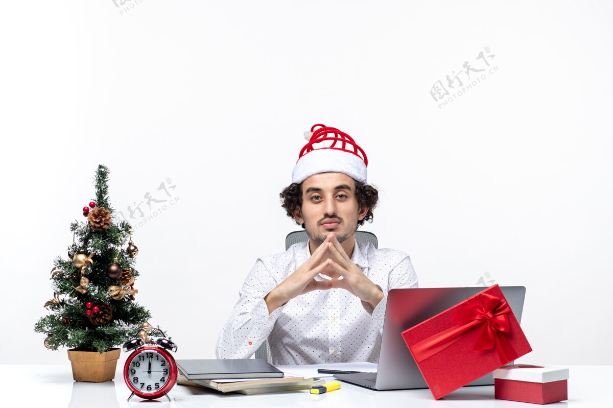 微笑满意自豪的年轻商人与有趣的圣诞老人帽子庆祝圣诞节在白色背景的办公室办公室微笑圣诞老人