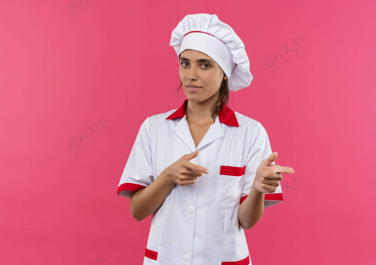 女高兴的年轻女厨师穿着厨师制服 指着旁边的复印空间边制服穿