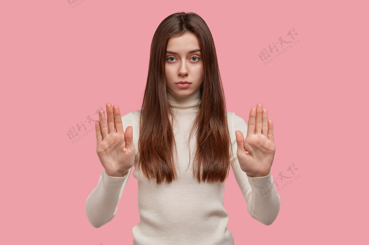 性格禁止标志严肃自信的女人展示手掌 展示停止标志 长直发 令人愉快的样子手掌拒绝女性