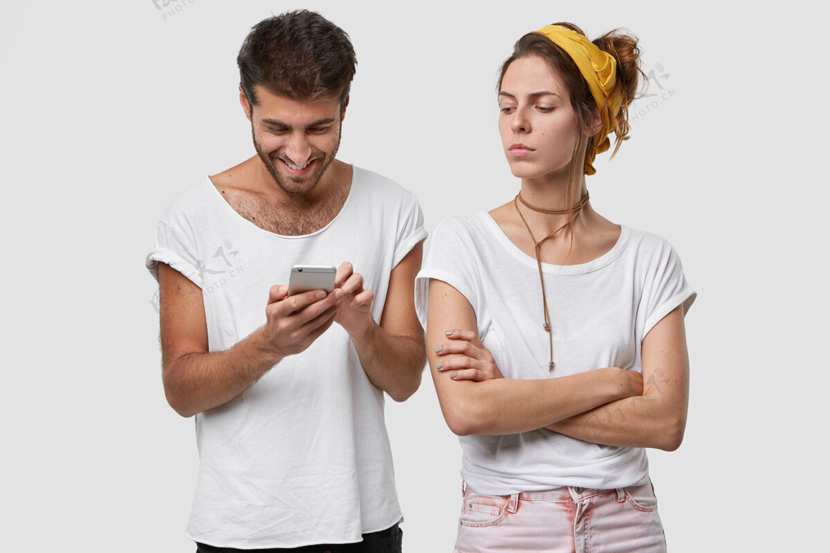 手机妒忌的妻子双臂合十 不悦地看着不理她的丈夫 玩手机游戏 和朋友聊天嫉妒打字电话
