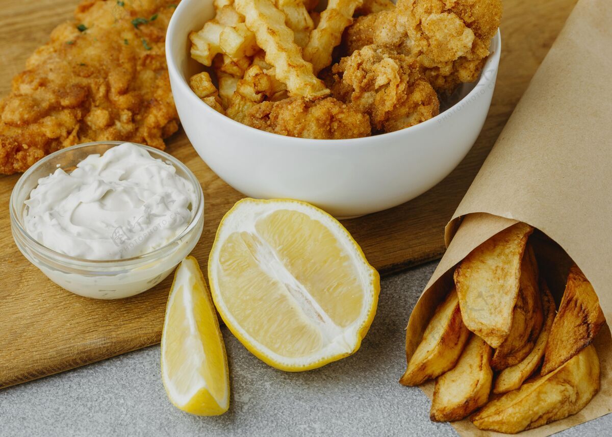 土豆高角度的鱼和薯条在碗和纸包装与柠檬柠檬薯条美食
